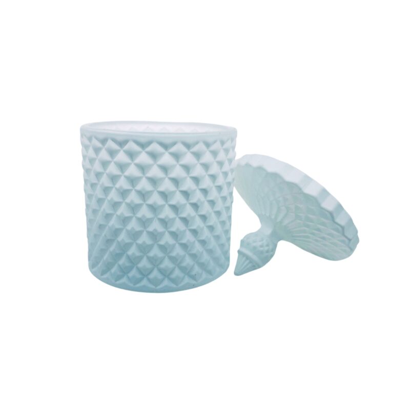 Pojemnik wraz z zakrętką do zalewu świec stojący na stole kolor biały mat zakrętką położna obok