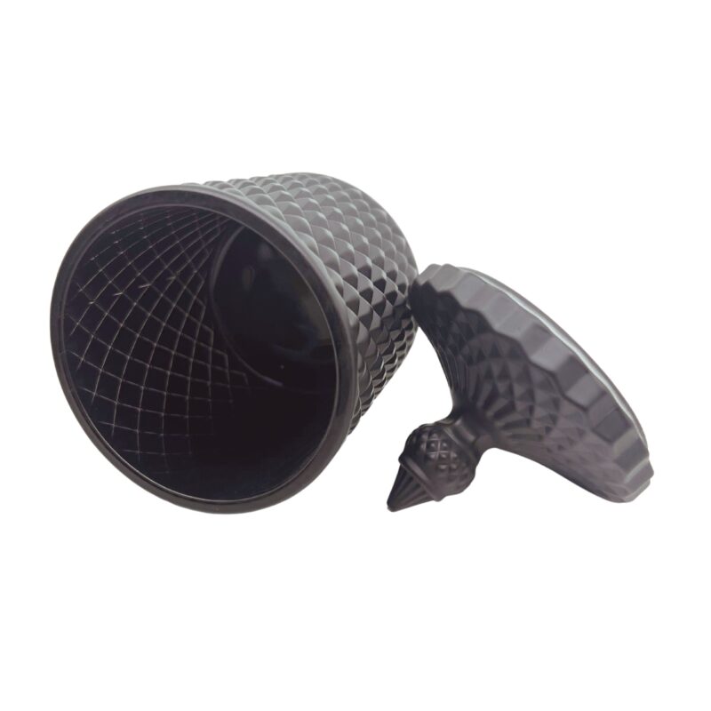 Pojemnik wraz z zakrętką do zalewu świec stojący na stole kolor czarny mat przewrócony na bok