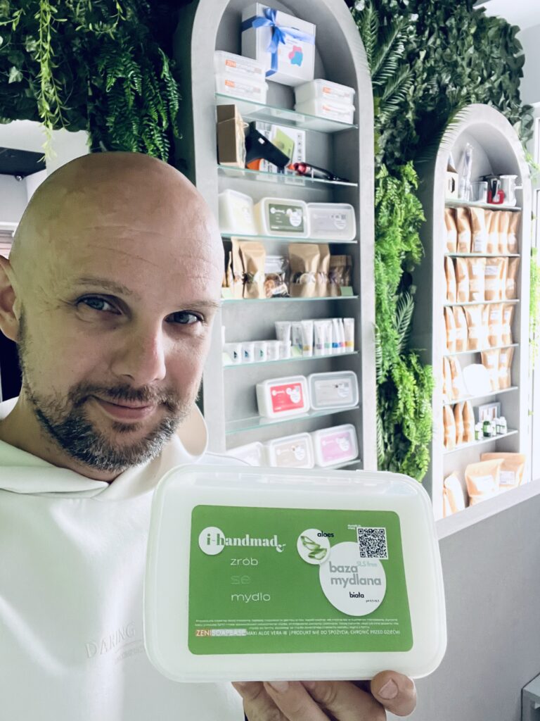 Sławek trzymający w reku Baze mydlana biała z aloesem w siedzibie firmy i-handmade.pl